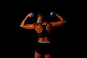Brutal athletic woman pumping up muscles with dumbbells. Sexy attractive fitness woman, trained female body, lifestyle portrait, caucasian model.