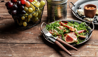 Delicious gourmet cheese, assortment of soft cheeses served with sliced sweet fresh figs and grapes on a rustic wooden background, catering, banner, menu, recipe, place for text