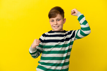 Little redhead boy isolated on yellow background celebrating a victory