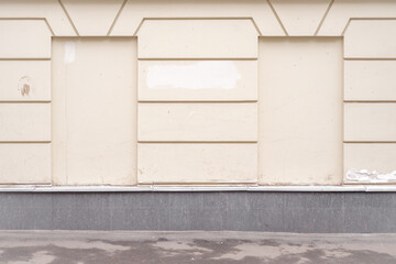 Old light yellow plastered painted wall with blocked windows