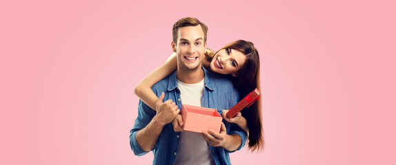 Holiday sales actions, rebates, discounts offers concept image - happy couple opening gift box, isolated over pink color background. Copy space for some text.