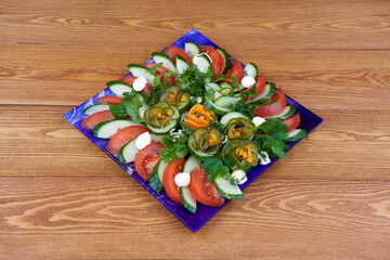 Beautifully sliced tomatoes and cucumbers, carrots on a round plate, for a festive table. Sliced vegetable salad. on a wooden background. close-up. food.