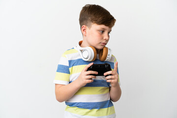 Fototapeta premium Little redhead boy holding a game pad isolated on white background looking to the side