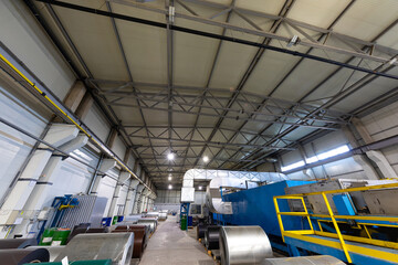 Photo shot of roll of painted galvanized steel sheet at cutting machine, ironworks and metalwork in factory. Plant concept