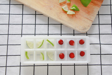 Ice cubes with fruits inside the ice cube tray. Summer menu. top view.
