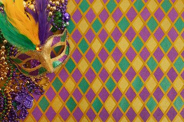 Frame of Mardi Gras Mask and colorful Mardi Gras Beads on diamond shaped background - obrazy, fototapety, plakaty