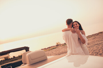 Photo of cute adorable married couple dressed white clothes driving car embracing smiling outdoors...