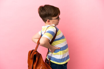 Little redhead caucasian boy isolated on pink background suffering from backache for having made an...