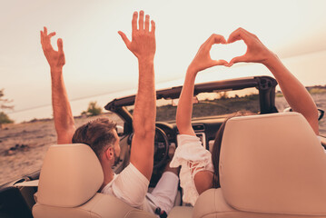 Photo of cheerful pretty husband wife wear white outfits smiling riding automobile rising arms...
