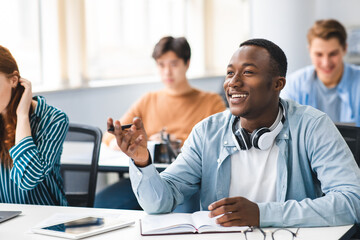 Smiling black student talking to teacher at classroom