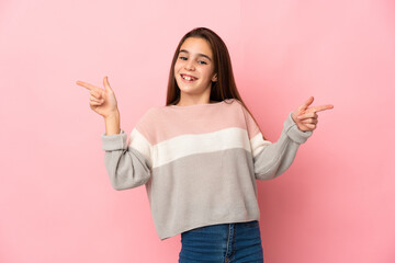 Little girl isolated on pink background pointing finger to the laterals and happy