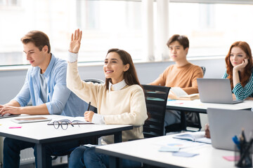 Portrait of female student raising hand at classroom