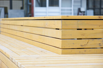 A wooden bench made of timber covered with yellow stain on the stylobate of a residential building under construction.