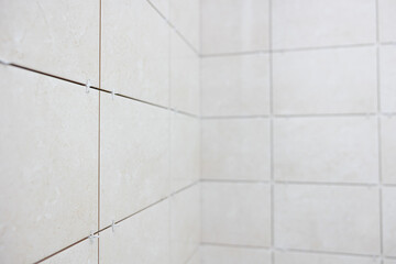 Installation and alignment of ceramic tiles in a white bathroom. Placed the plastic crosses between the tiles.