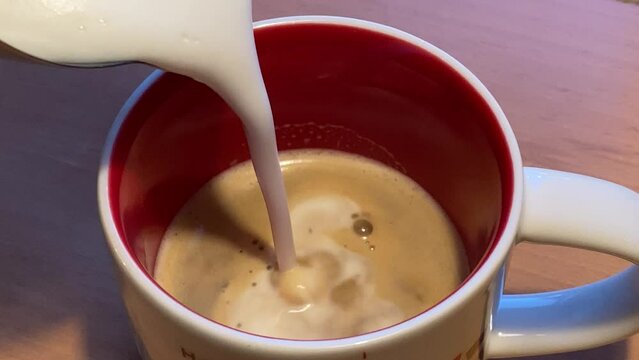 Nahaufnahme, Milch, Milchschaum in Kaffe gie&szlig;en, Cappuccino