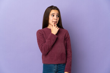 Little girl isolated on purple background nervous and scared