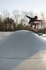 Giovane skater durante una sessione di allenamento in uno skate park cittadino di cemento