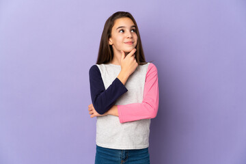 Little girl isolated on purple background thinking an idea while looking up