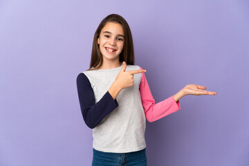 Little girl isolated on purple background holding copyspace imaginary on the palm to insert an ad