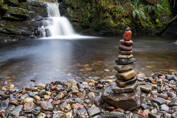 Stone stacking or rock balancing at waterfall. Zen balanced pebbles stack art. Beautiful peaceful calm nature long exposure background. Wellness, relaxation concept. Brecon Beacons, Wales, UK