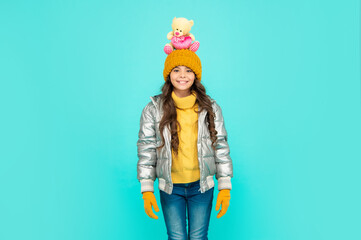 happy kid in puffer jacket and hat. childhood. teen girl hold toy bear.