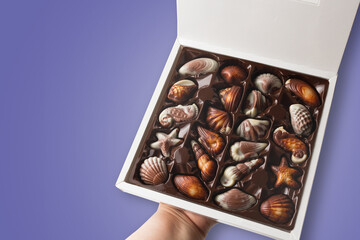 Box of chocolates on lilac background.