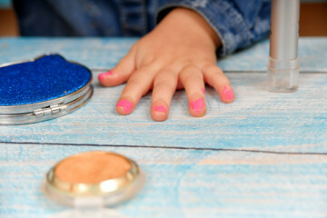 The little girl painted her nails with nail polish herself and waits for them to dry.