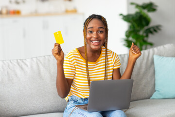 Excited black woman with credit card and laptop, copy space
