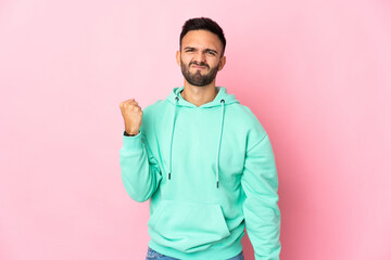 Young caucasian man isolated on pink background with unhappy expression