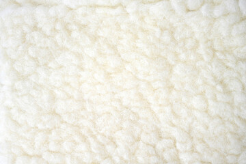White curly short sheep's wool is laid out on the table. View from above