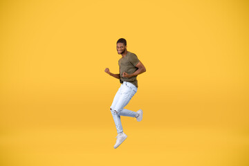 Fototapeta na wymiar Joy of victory. Excited african american man gesturing yes and jumping over yellow background, free space