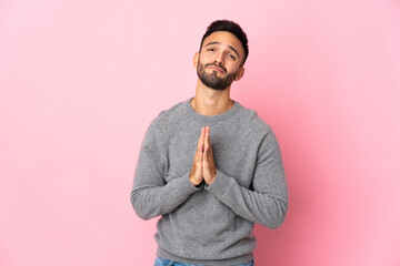 Young caucasian man isolated on pink background keeps palm together. Person asks for something