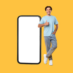 Happy guy showing white empty smartphone screen and thumbs up