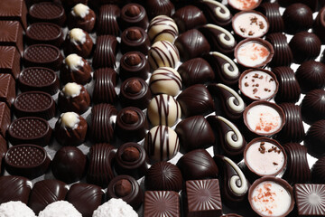 Many different delicious chocolate candies as background, closeup view