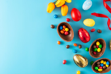 Fototapeta na wymiar Colorful chocolate Easter eggs on blue bckground. Top view. Copy space