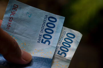An Asian child holds Indonesian money in shallow focus. Saving and giving concept