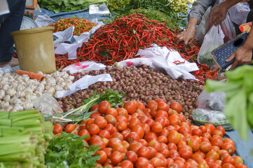 Fresh produce displayed at a local market with buyers passing by and hunting for cheaper price to fit the budget