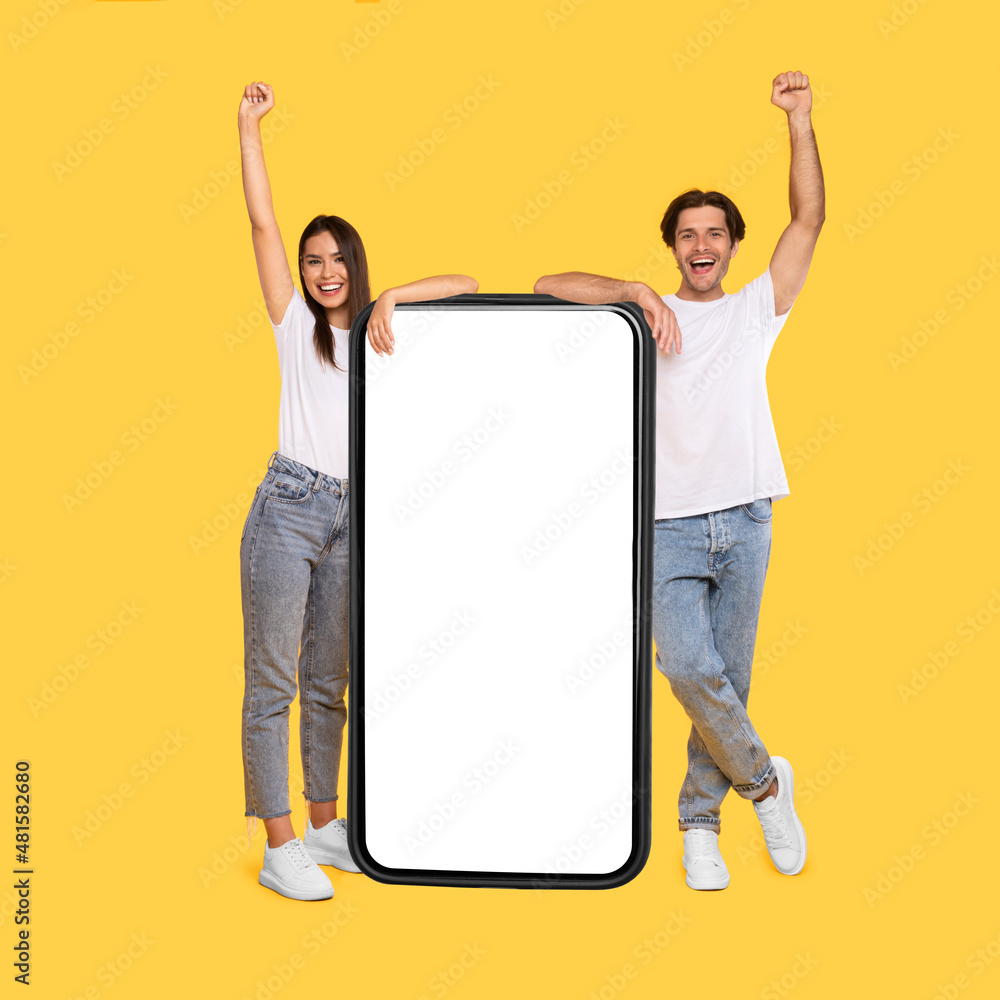 Poster couple showing white empty smartphone screen and making win gesture