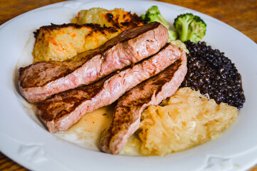 Close up of a plate of beef steak slices with sauerkraut, lentils and brussel sprouts for high protein ketogenic meal 