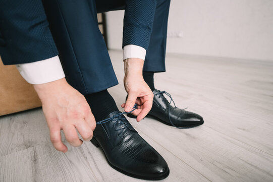 A man in a suit, the groom, close-up puts on shoes, ties his shoelaces