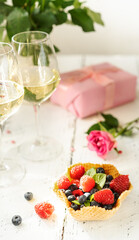 S.Valentine's Day concept. Mix of berries in a waffle basket, sparkling wine in two glasses, roses and gift
