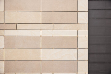 Modern ventilated facade tiles in beige and brown colors on the wall.