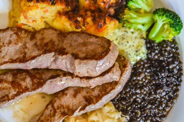 Close up of a plate of beef steak slices with sauerkraut, lentils and brussel sprouts for high protein ketogenic meal 