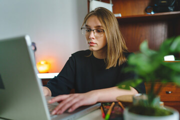 One young caucasian woman female student working on her laptop computer sitting at the table at...