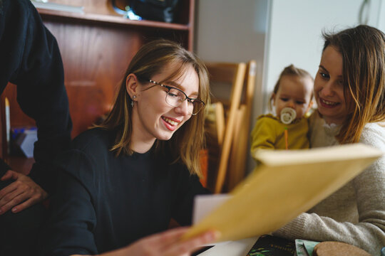 Group of people young woman caucasian female student sitting at home with her friends and family holding envelope with mail letter happy exited smiling reading entry test results success concept