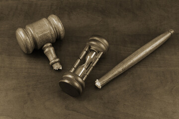 Hourglass and broken judge gavel on wooden background
