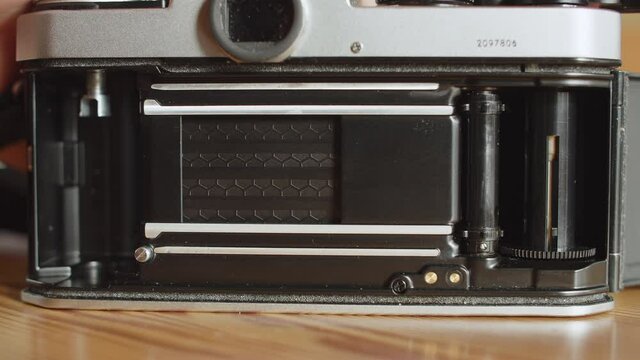 View on the opened back of an analog camera. The shutter with an honeycomb-pattern gets reset/cocked, the film take up spool rotates as the film advance lever gets wound and the shutter gets fired