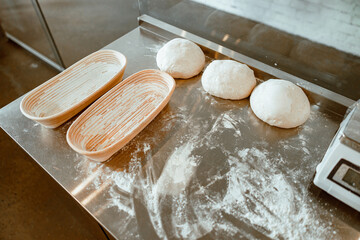 Dishes, raw dough and scattered flour on metal table in bakery workshop