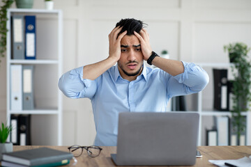 Desperate Arab businessman having too much work, making mistake, cannot meet deadline, suffering from headache at work
