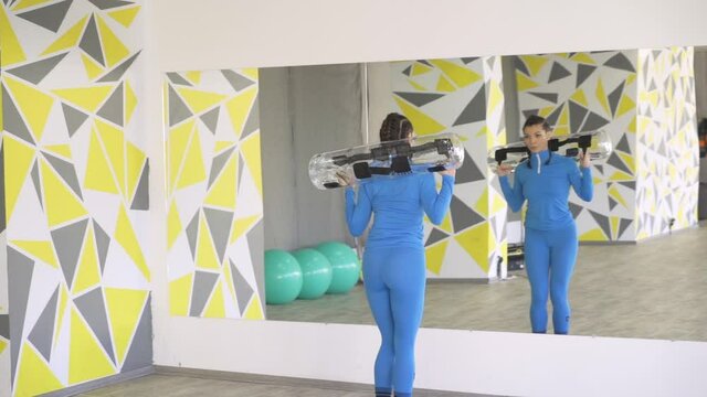 Beautiful sporty brunette woman in blue sportswear lifting aqua bag